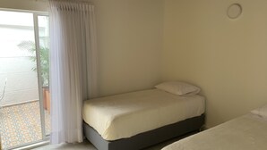 A bedroom with a bed, a window with curtains, and a view of the outside.