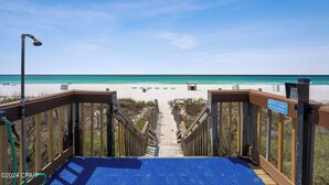 Une promenade en bois menant à une plage, avec un panneau indiquant le code d’accès à la porte.