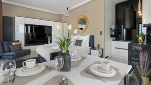 Et moderne hotelværelse med seng, spiseplads til to, fjernsyn og tekøkken.