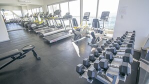 Un gimnasio con cintas de correr, elípticas y mancuernas dispuestas en filas.
