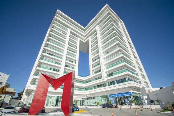 A modern hotel with a distinctive red sculpture in front, featuring a prominent entrance and a clear view of the surrounding area. - Beautiful Malecon and Beyond 1502 Torre eMe (Mazatlan)