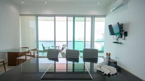 Una sala de conferencias moderna con una mesa de vidrio, cuatro sillas, un televisor y un balcón con vistas.