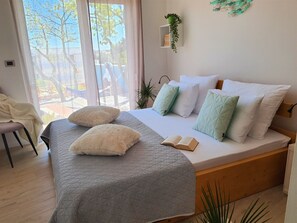 A bedroom with a bed, pillows, a bedside table, a chair, and a window with a view of trees. - Villa Ernesta with Pool (Pula)