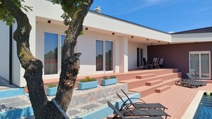 Une maison moderne dotée d’un patio, d’une piscine et de mobilier d’extérieur.