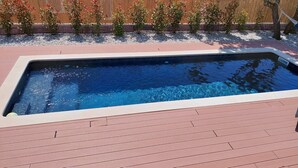 Une piscine rectangulaire entourée d’une terrasse en bois.
