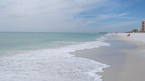 A beach with a sandy shore and calm waves. - Gulf View, Updated Condo, Steps from the ocean, Short Drive to Shopping (Destin)