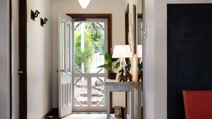 Un pasillo con una puerta de madera que da a una habitación luminosa con vistas a zonas verdes.
