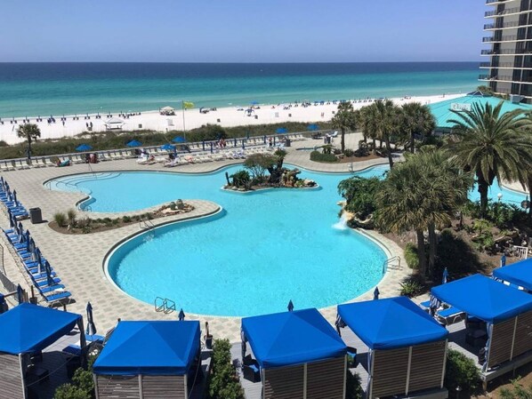 Ein Resort mit großem Pool, Strand und Palmen.