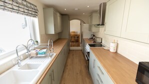 A narrow kitchen with a wooden countertop, a sink, and a microwave. - ⭐️Stunning Holiday Home⭐️ - Centre of Coniston - 3 bedroom  (Coniston)