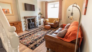 A cozy living room with a fireplace, leather sofa, and a patterned rug. - ⭐️Stunning Holiday Home⭐️ - Centre of Coniston - 3 bedroom  (Coniston)