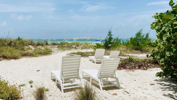 A beach with white lounge chairs and a clear view of the ocean. - Sailfish Gulf Suites #4, Garden Views, Steps from the Beach (Holmes Beach)