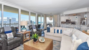 A modern living room with a sofa, chairs, a coffee table, and a view of the city through large windows.