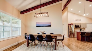 A dining area with a wooden table, black chairs, and a hanging light fixture.