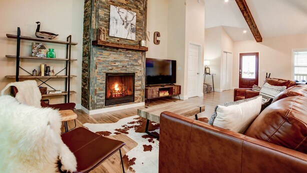 A living room with a fireplace, leather furniture, a TV, and a bookshelf.