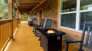 A covered wooden deck with outdoor seating and a built-in fire feature.