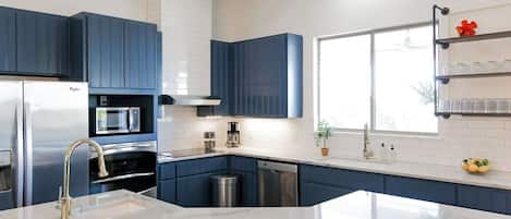 Una cocina moderna con armarios azules, una encimera blanca y una isla grande con fregadero.