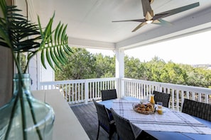 A covered outdoor dining area with a table set for breakfast, surrounded by white railings and overlooking a lush landscape. - Pool/Spa | 14 Beds | Sleeps 28 - WalkerVR Sundown Escape (Austin)