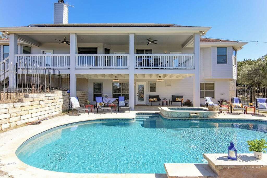 A two-story house with a swimming pool, outdoor seating, and a covered patio area.