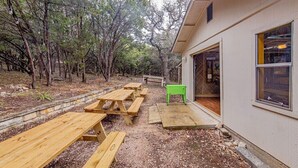 An outdoor area with picnic tables and a building with a window. - Pool/Spa | 14 Beds | Sleeps 28 - WalkerVR Sundown Escape (Austin)