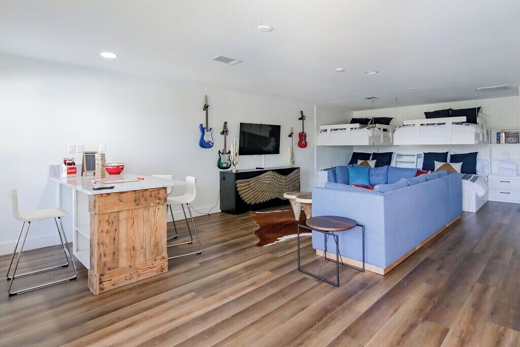 Ein stilvolles Wohnzimmer mit einem Holzesstisch, einem blauen Sofa und einem an der Wand befestigten Fernseher.