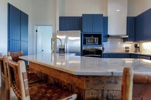Una cocina moderna con armarios azules, un refrigerador de acero inoxidable, un microondas y un horno empotrado.
