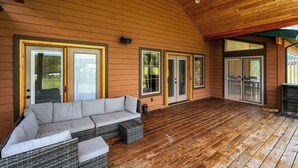 A covered porch with a wicker sofa, sliding glass doors, and a wooden ceiling.