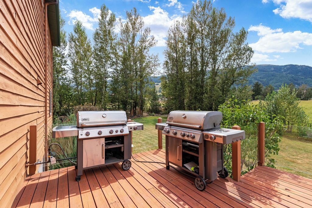 Deux barbecues portables sur une terrasse en bois, avec vue sur les arbres et les collines.