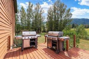 Deux barbecues portables sur une terrasse en bois, avec vue sur les arbres et les collines.