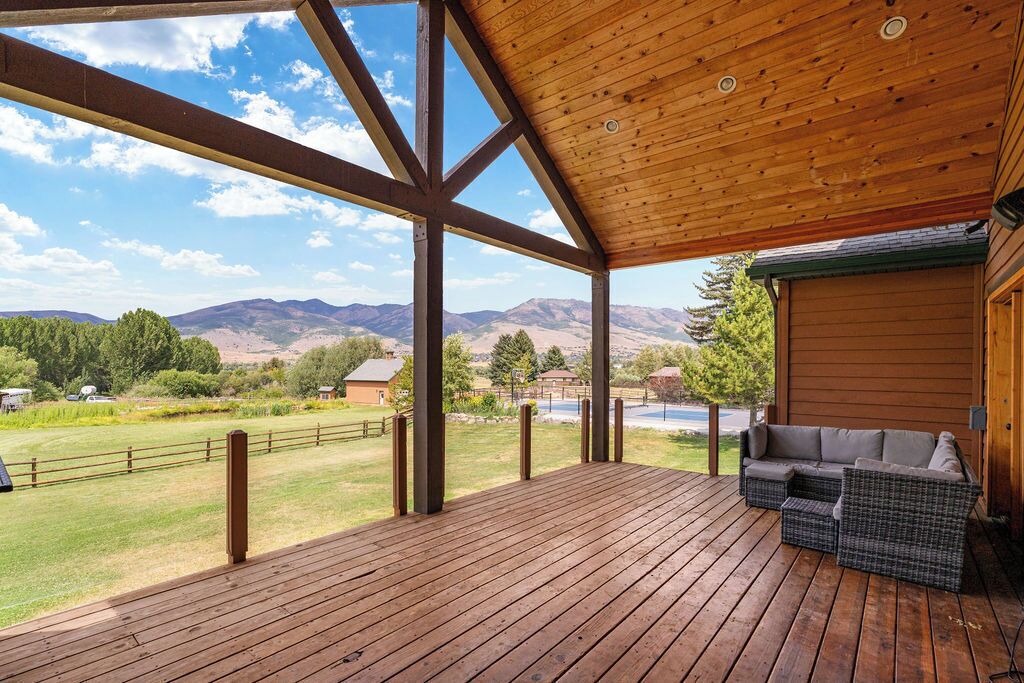 A wooden deck with a view of mountains and a fenced area.