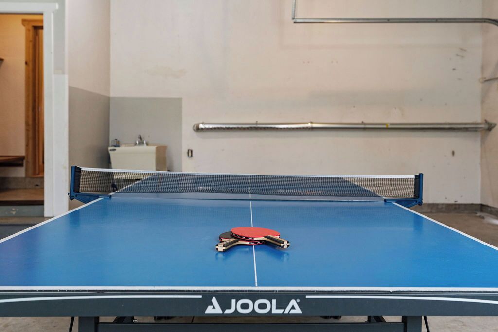 A table tennis table with a net and a paddle in the center, branded with 'AJOLA'.