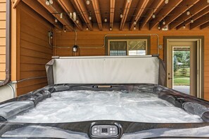 Un jacuzzi con panel de control, rodeado de paredes de madera y un techo con vigas a la vista.