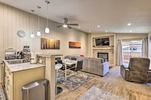 Cozy living space with a dining table, sofa, and recliner, featuring a fireplace and flat-screen TV.