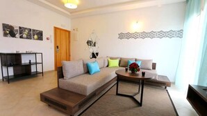 Una sala de estar moderna con un sofá, una mesa de centro y una mesita auxiliar. Hay una puerta y un espejo en la pared.
