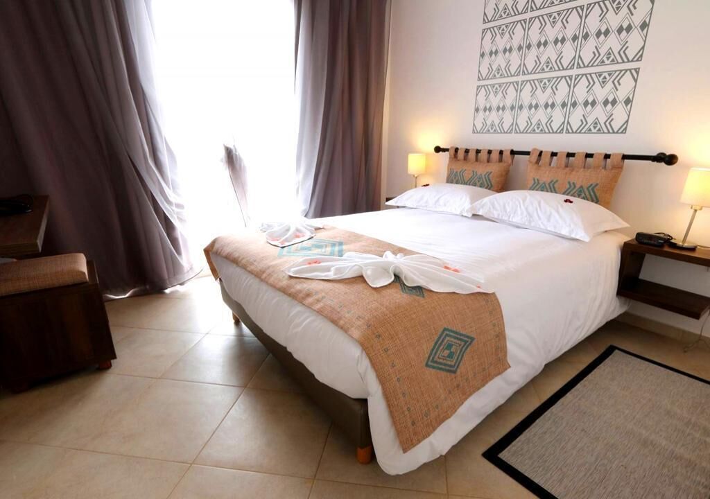 Habitació d'hotel amb un llit, dues taules de nit, una cadira i un mur amb un disseny.