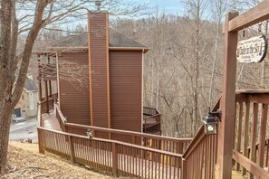 A wooden cabin with a balcony, a chimney, and a sign welcoming visitors to Gatlinburg, TN.