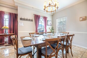 Comedor con una mesa de madera dispuesta para seis personas, rodeada de sillas de madera con asientos acolchados.