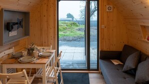 En hyggelig hytte med træpaneler, et spiseområde med et bord dækket til to samt en sofa.