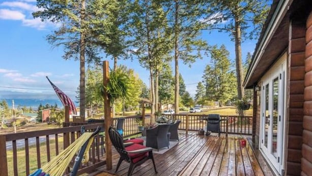 Eine Holzterrasse mit Gartenmöbeln, einer Hängematte und Blick auf den Ozean.