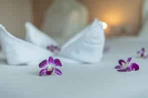 A neatly made bed with white pillows and purple orchid flowers. - Ricos Hotel Patong (Patong)