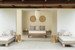 Una habitación con una cama, dos sofás, una mesa de centro de madera y dos tapices de pared tejidos.