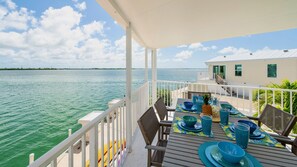 A deck with a table set for dining, overlooking a body of water. - **TURTLE COVE VIEWS** Cottage/ Boat Slip/ Pool + Last Key White Glove Service... (Cudjoe Key)