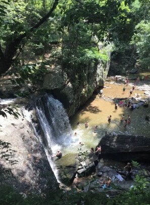 Ein natürlicher Wasserfall, an dem sich Menschen im Wasser vergnügen.
