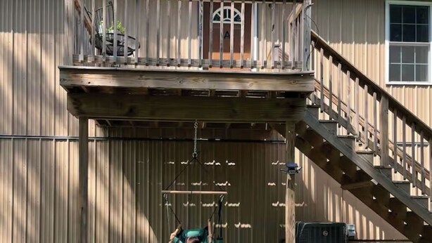 Un bâtiment à deux étages doté d’un balcon, d’une chaise suspendue et d’un escalier menant à l’étage supérieur.