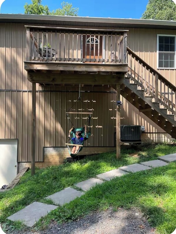 A two-story building with a balcony, a swing chair, and a staircase leading to the upper level.