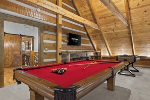 A pool table with balls, a television, and a wooden ceiling in a room with a rustic design. - Waterfall Pool · Barrel Sauna + Hot Tub · Cabin · 15 Private Acres (Mineral Bluff)