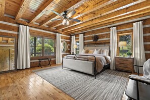 Un dormitorio con cama, ventilador de techo y ventanas grandes.
