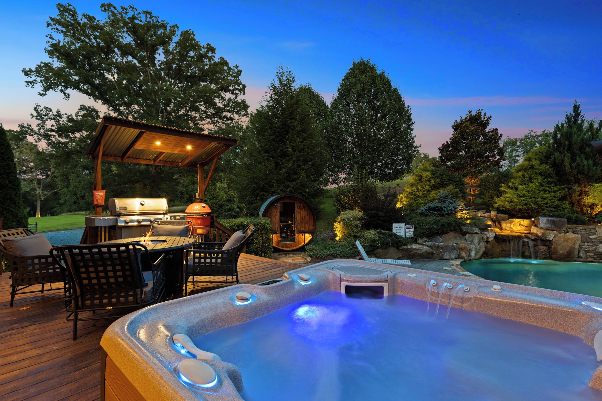 A hot tub, outdoor grill, and seating area on a wooden deck.