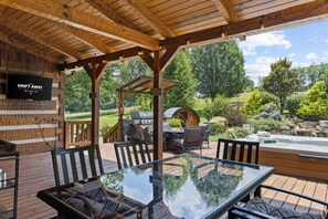 An outdoor patio with a glass table, chairs, and a grill area.