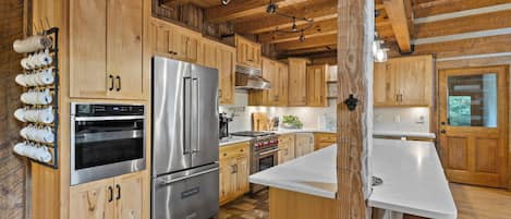 A kitchen with wooden cabinets, stainless steel appliances, and a marble countertop.
