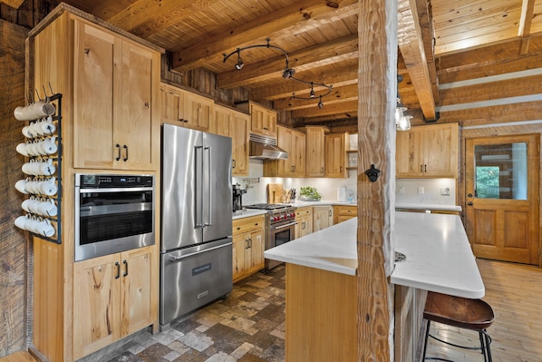 A kitchen with wooden cabinets, stainless steel appliances, and a marble countertop.